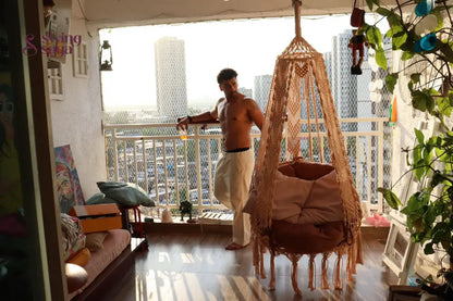 Hanging macrame chair hammock swing with a mattress and a cushion.