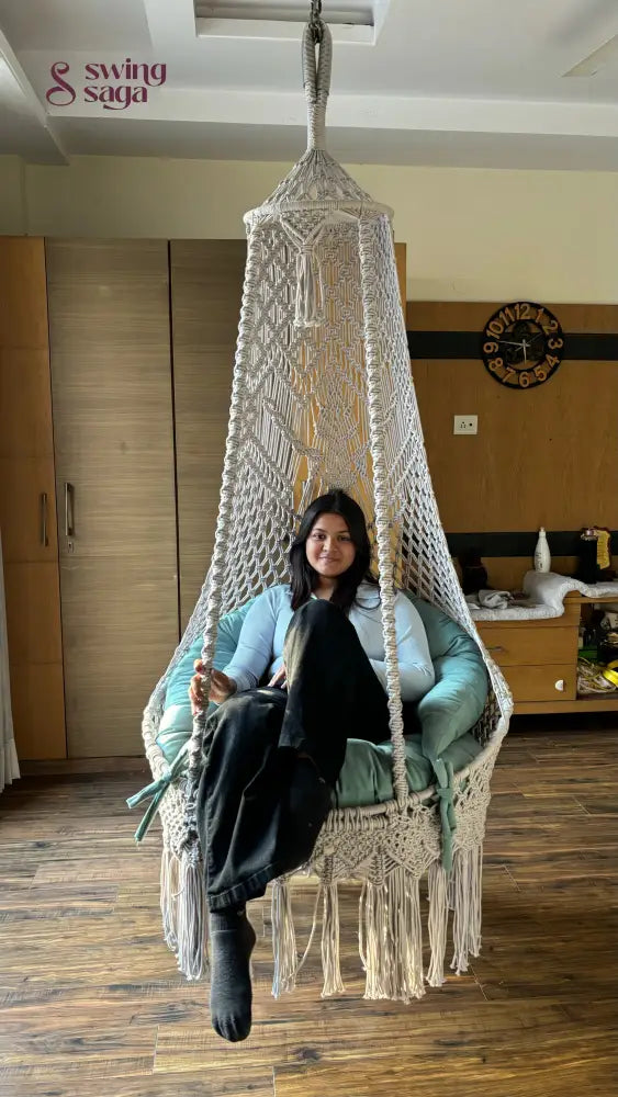 A girl sitting on a white hanging chair swing.