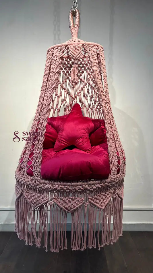 Pink macrame hanging swing for toddlers.