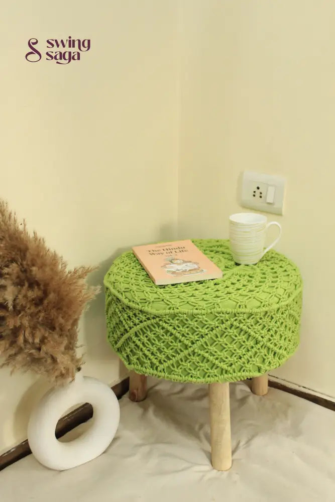 Bohemian-style green macrame footstool with detailed knotting and solid wooden base.
