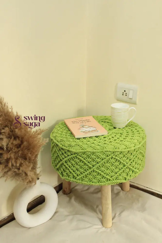 Bohemian-style green macrame footstool with detailed knotting and solid wooden base.