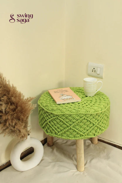 Bohemian-style green macrame footstool with detailed knotting and solid wooden base.