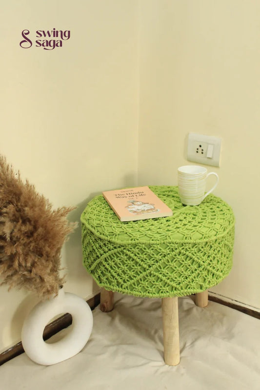 Bohemian-style green macrame footstool with detailed knotting and solid wooden base.